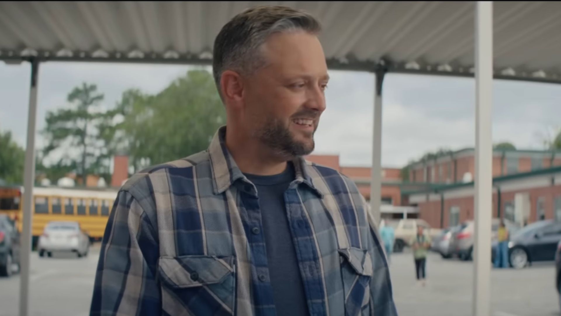 Nate Bargatze as Nate in The Breadwinner. He's wearing a flannel shirt and arriving at the school for pickup.