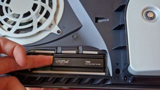 A Crucial T500 being inserted into a PS5's M.2 bay