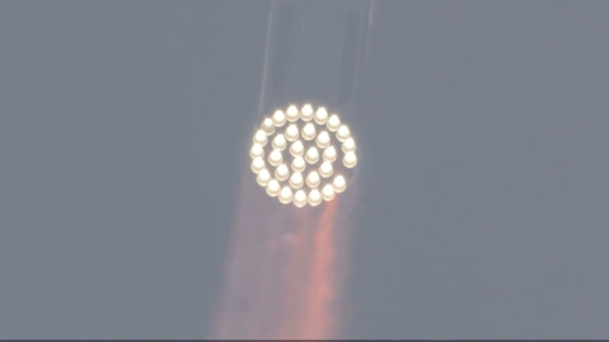 a large silver-and-black rocket launches above a plume of fire