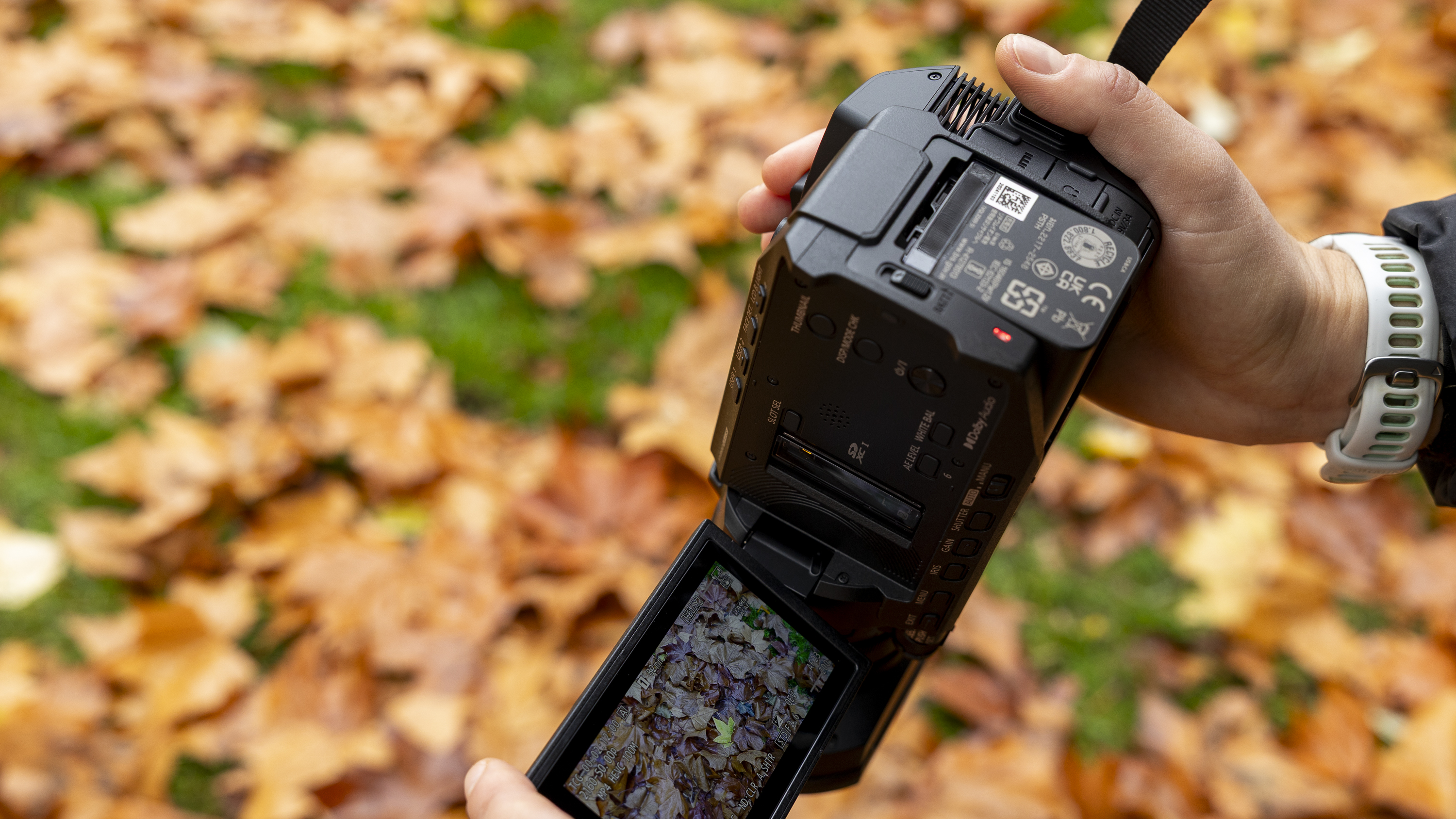 The Panasonic HC-X1200 camcorder held by a female photographer against an orange autumnal backdrop