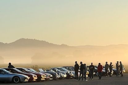 Morning at a classic car event in Northern California, with a mountain view behind classic cars lined up. It is foggy and people are milling about, looking at the cars.