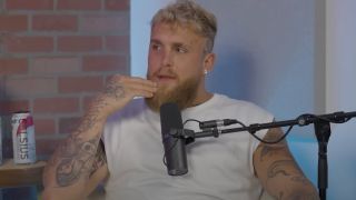 Jake Paul wearing a white shirt and touching his face