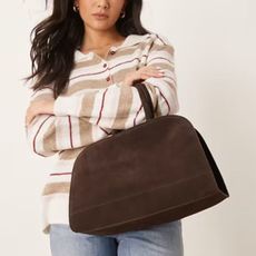 Woman wears striped jumper, blue jeans and brown suede handbag