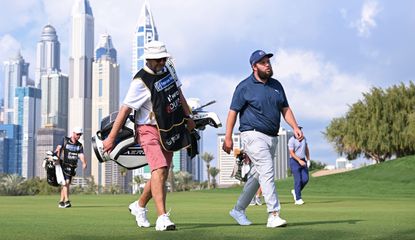 Beef walks along the fairway with the Dubai skyscrapers behind him