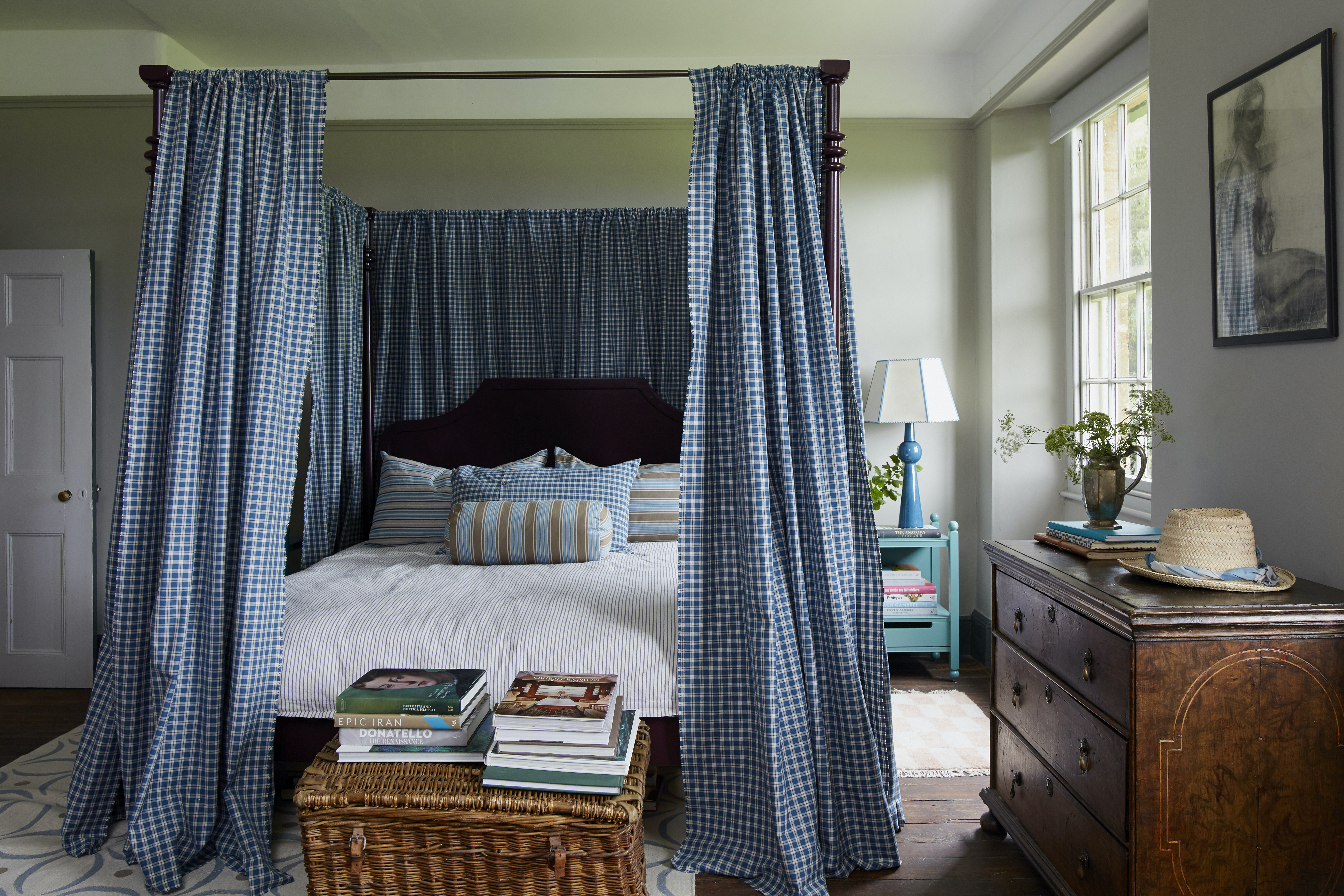 A four poster bed with blue gingham curtains
