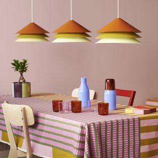A dining table with three pendant shades and brightly colored furnishings