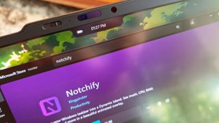 Close-up of a laptop screen showing a black notch overlay with a battery icon and time display above the Microsoft Store page for the Notchify app.