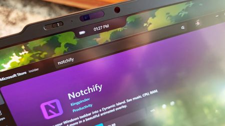 Close-up of a laptop screen showing a black notch overlay with a battery icon and time display above the Microsoft Store page for the Notchify app.
