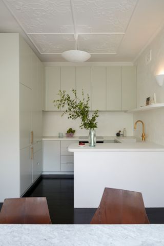 A kitchen with white cabinets and dark flooring