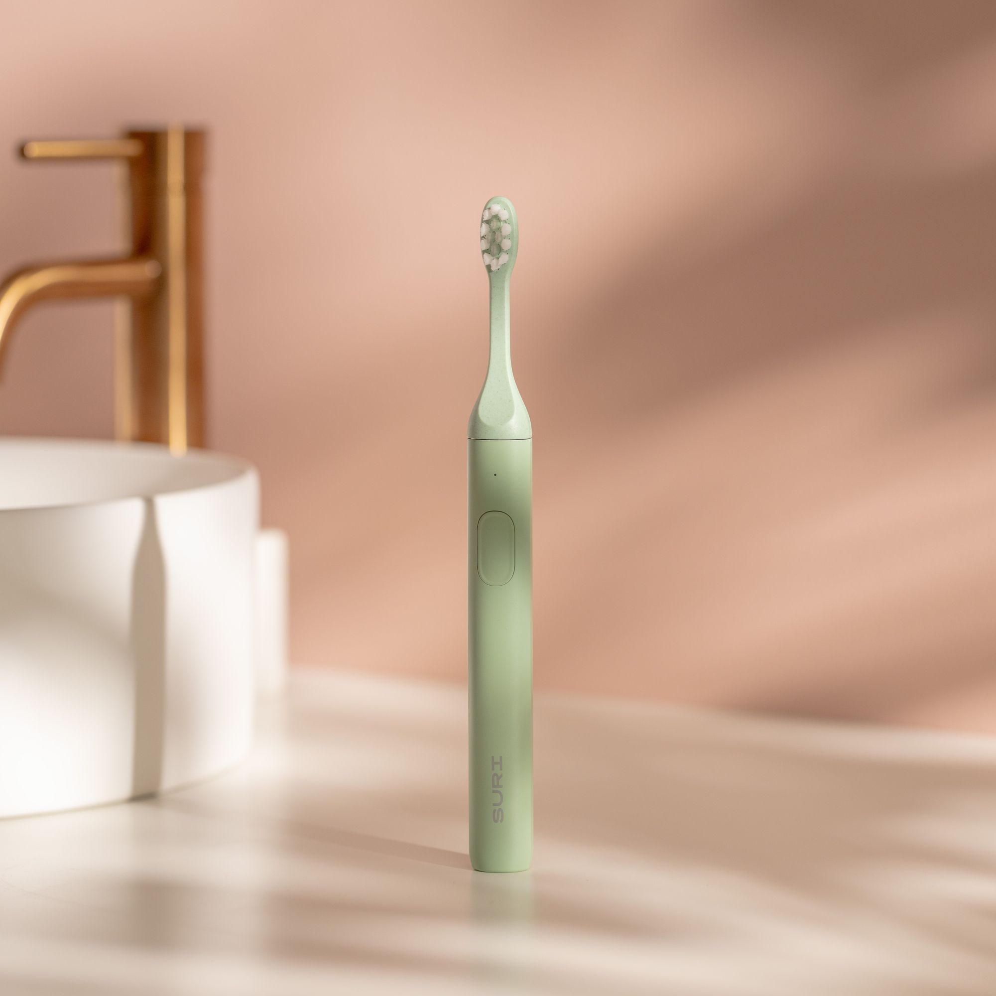 Suri electric toothbrush next to bathroom sink