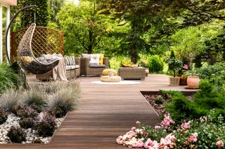 Decked bath with hammock chair, long grasses and greenery around border