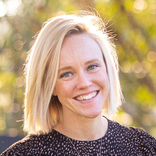 Image of a woman in a black blouse standing outside.