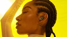 A woman in yellow wearing Bose QuietComfort Ultra Earbuds