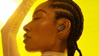 A woman in yellow wearing Bose QuietComfort Ultra Earbuds
