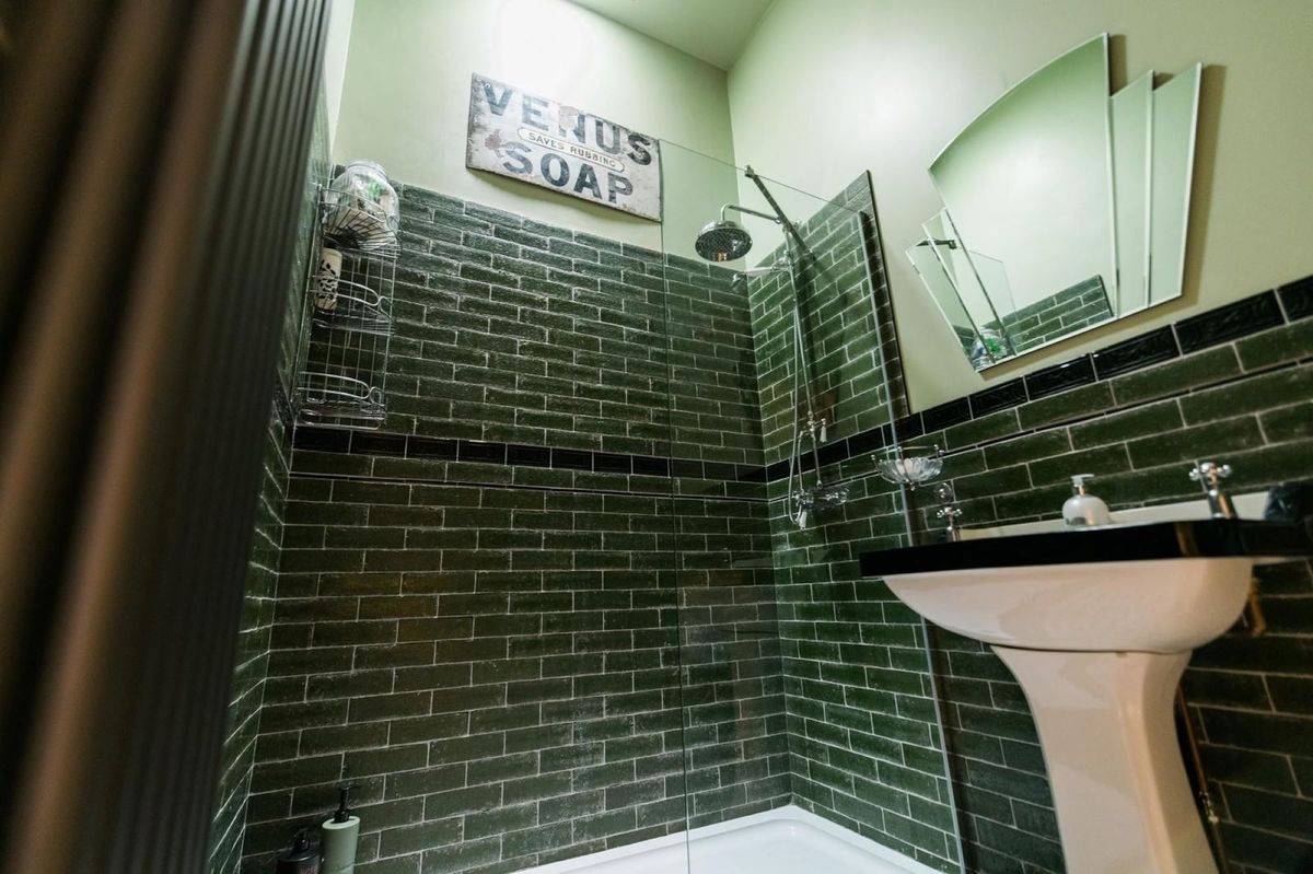 A green tiled bathroom with a walk-in bathroom and sink