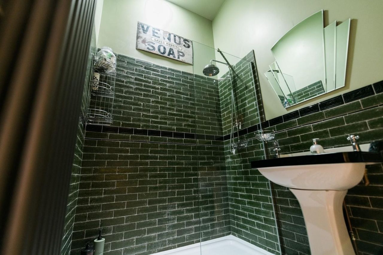 A green tiled bathroom with a walk-in bathroom and sink