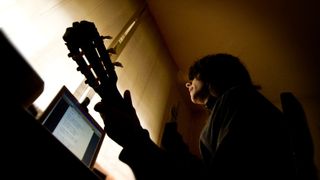 Musician recording acoustic guitar using computer