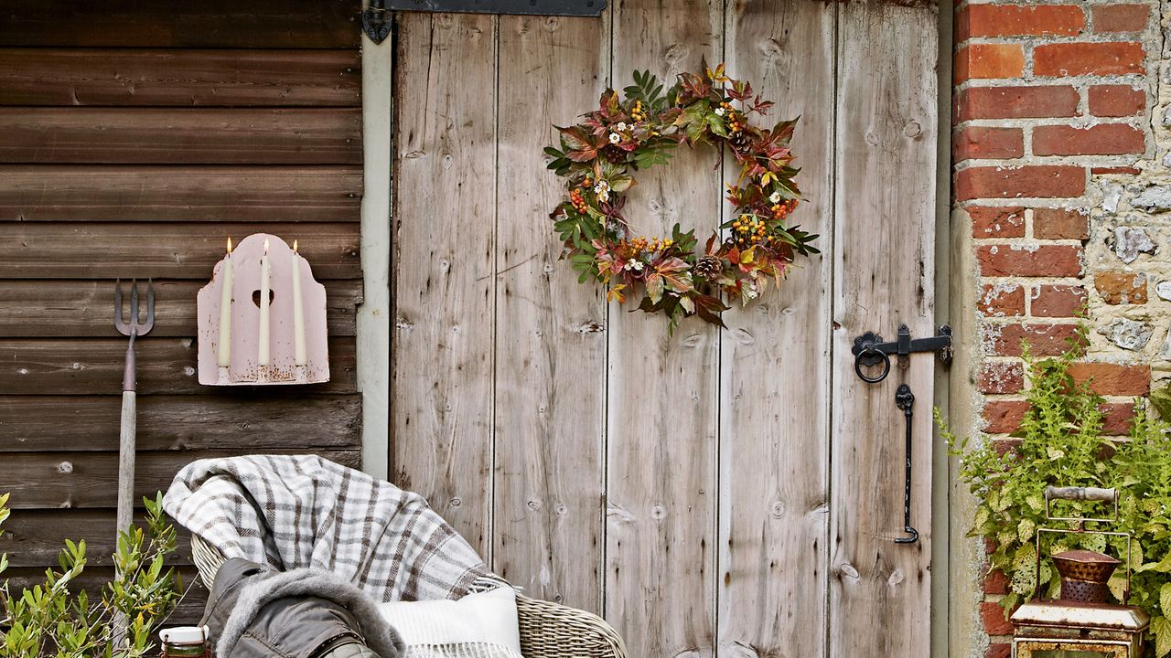 Autumn wreath on a wooden door with wicker chair