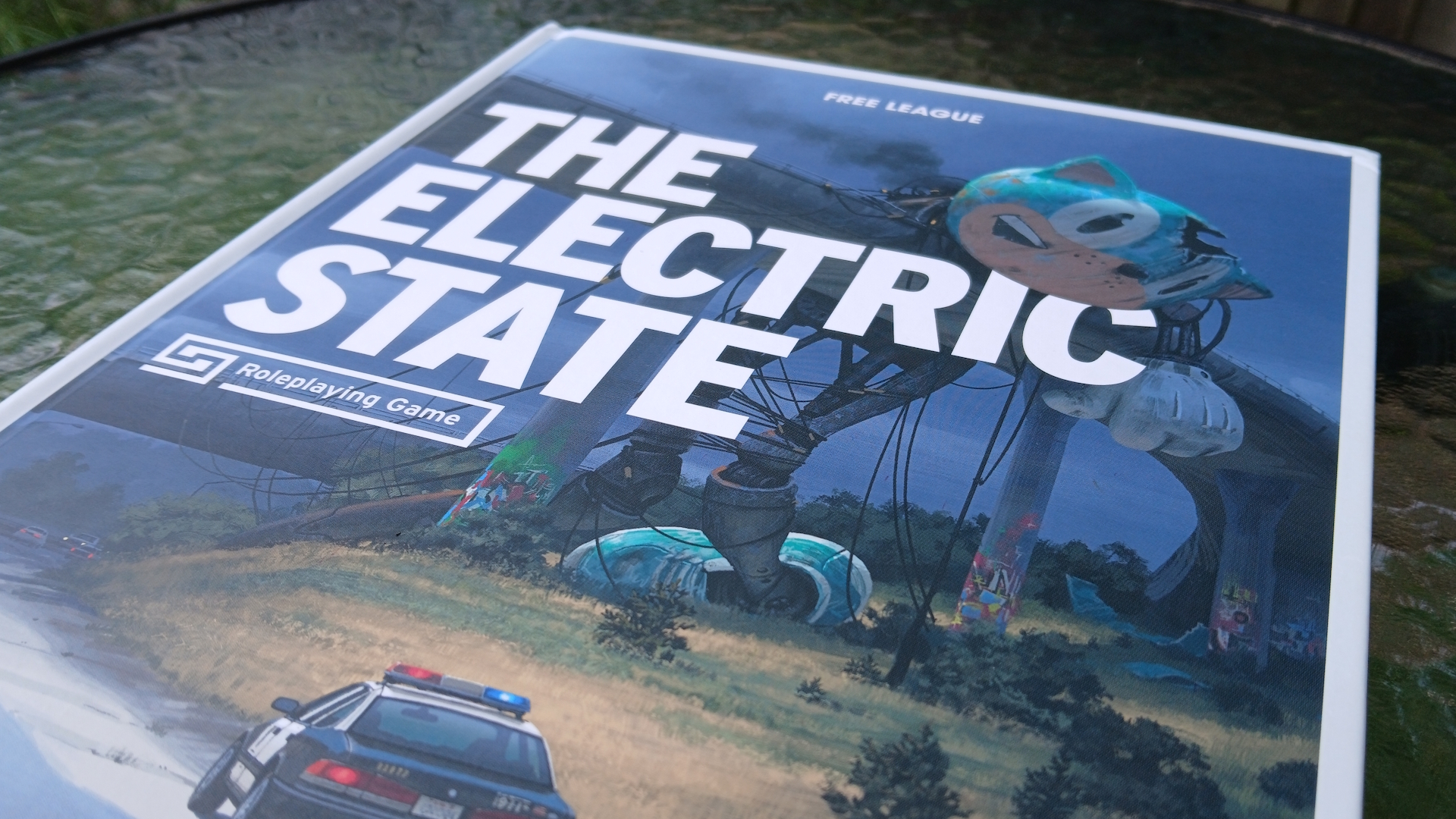 The Electric State core rulebook on a glass table