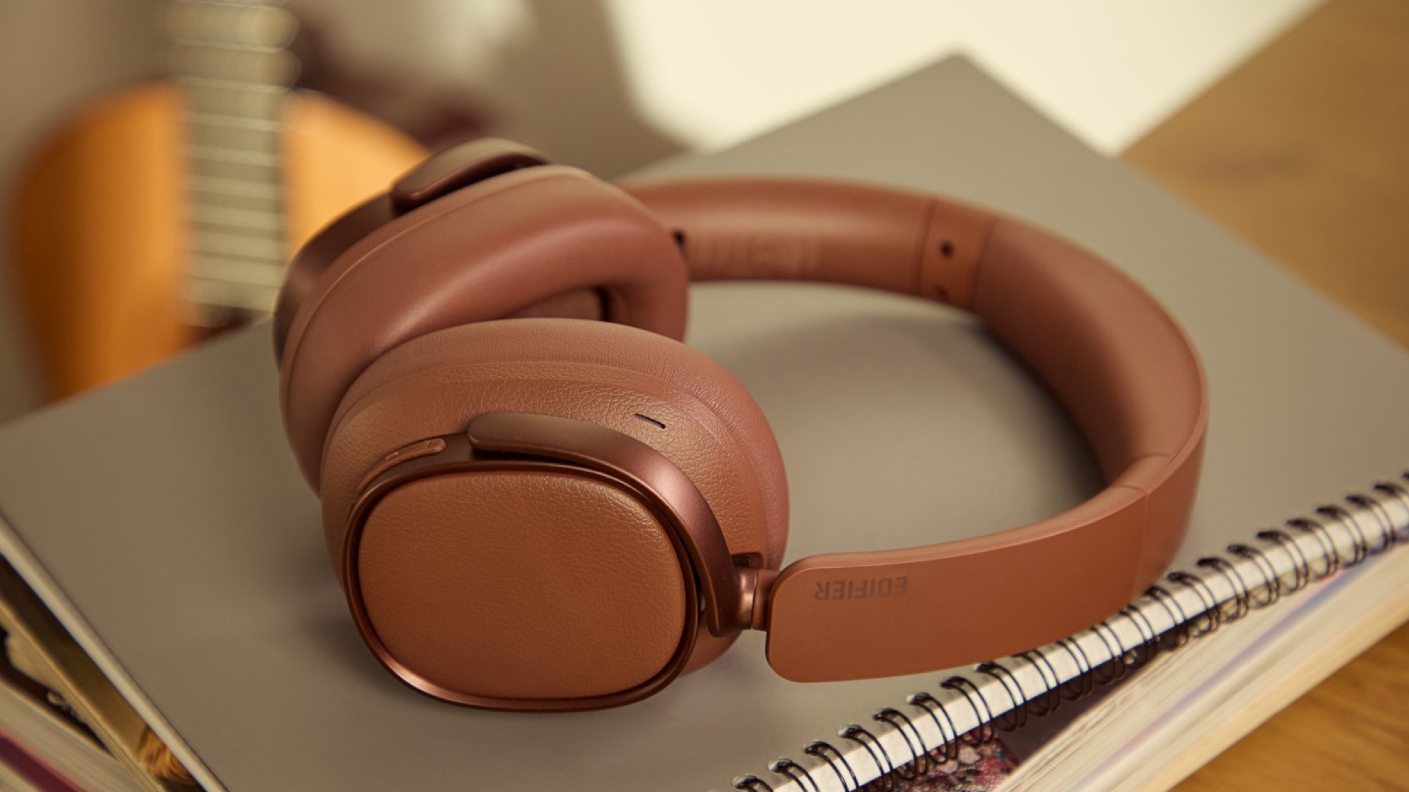 Edifier ES850NB over-ear headphones in brown sat on top of a spiral notebook on a desk or similar furniture