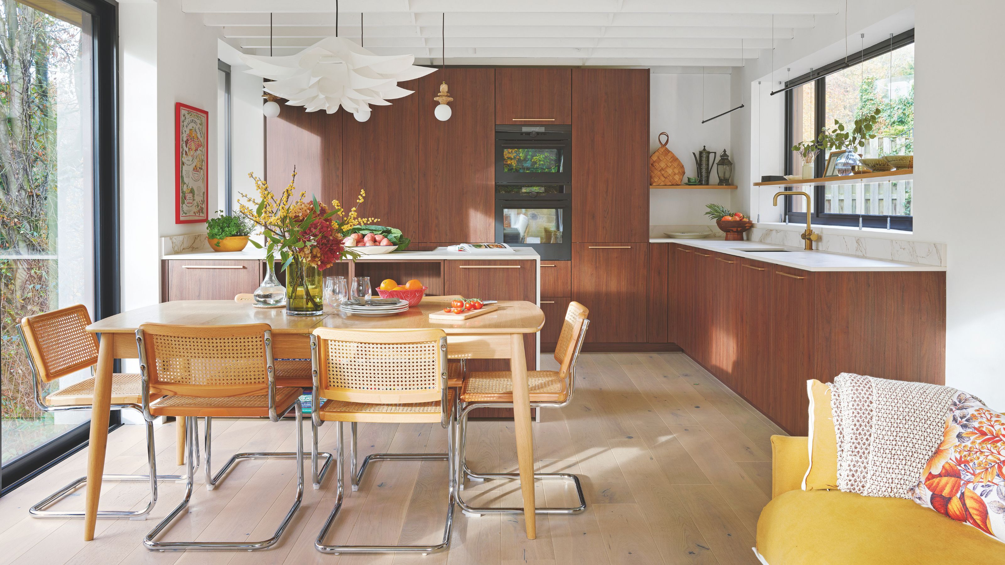 Open plan kitchen diner with wooden kitchen cabinets, a wooden dining room table, and wooden flooring