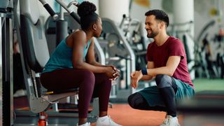 A man and woman chat at the gym