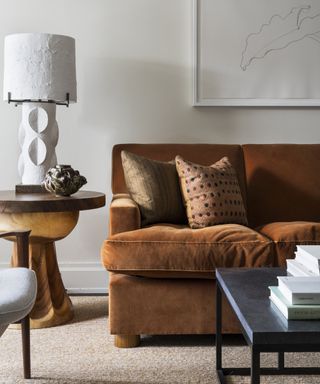 Small living room lighting with an orange-brown sofa, white walls and white plaster table lamp
