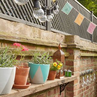 garden bricked wall with wooden shelves and pots and light bulbs