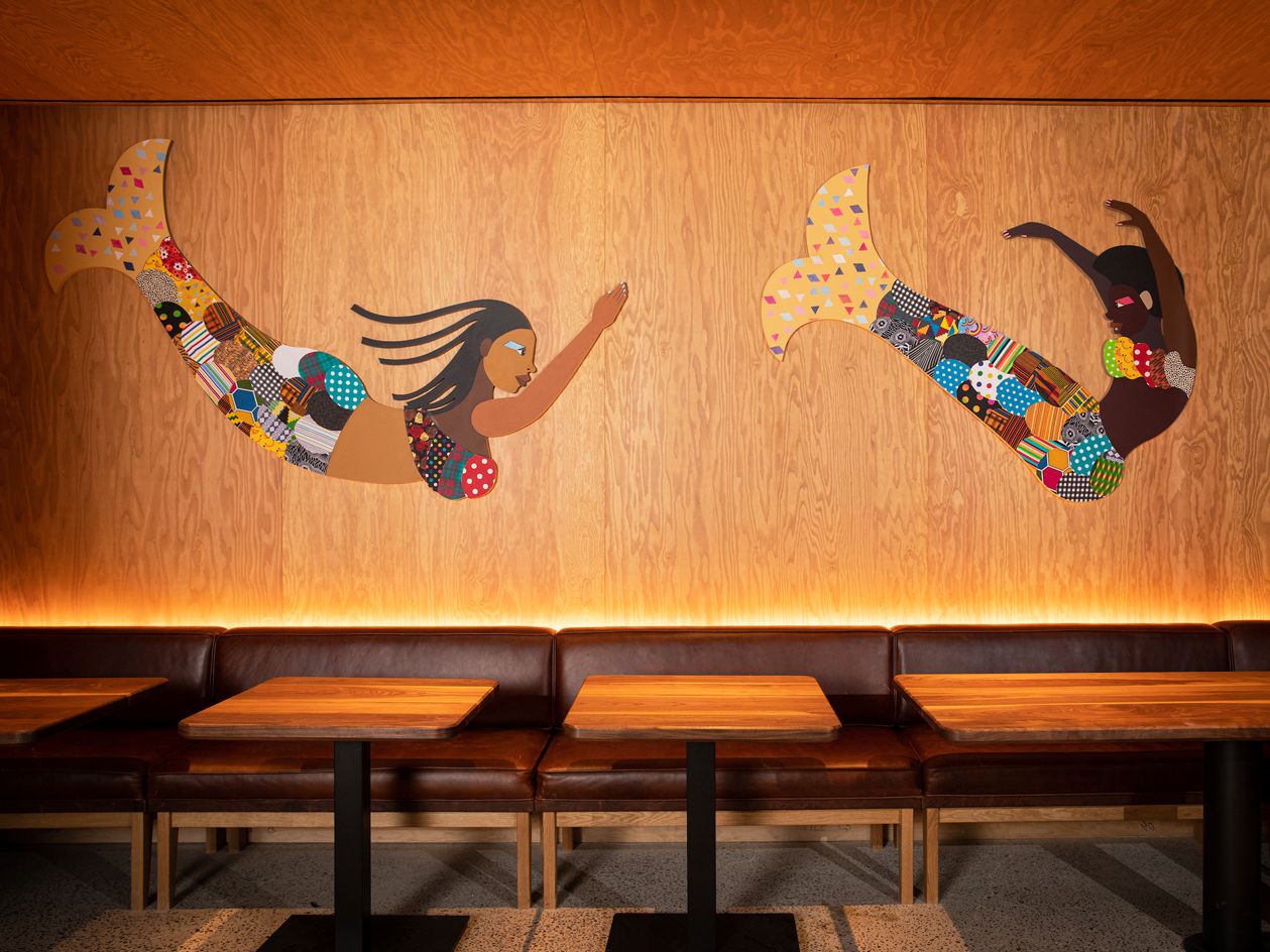 Artwork Black mermaids by Derrick Adams on wooden wall at Hav &amp; Mar restaurant in New York