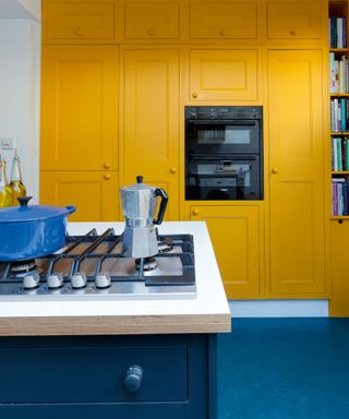 yellow kitchen with white countertops, blue le creuset casserole dish and built in microwave