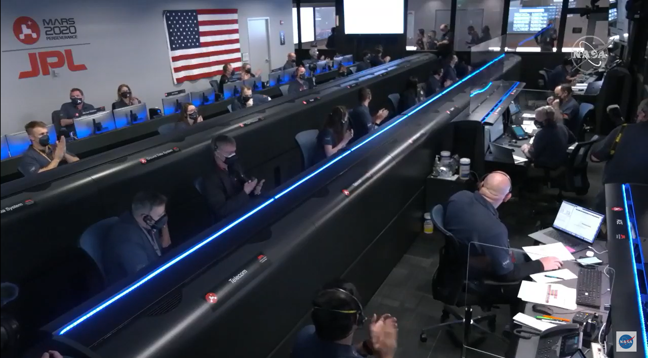 Perseverance personnel in mission control applaud a milestone in the mission's landing procedure.