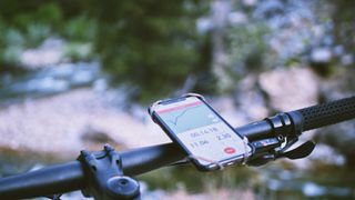 A close up of a phone mounted to some mountain bike handlebars, with Strava running in navigation mode