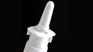 A close-up of the tip of a nasal spray bottle