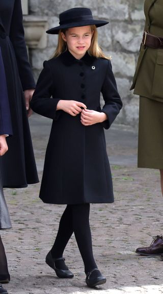 Princess Charlotte wearing a black dress coat and hat with a horseshoe brooch