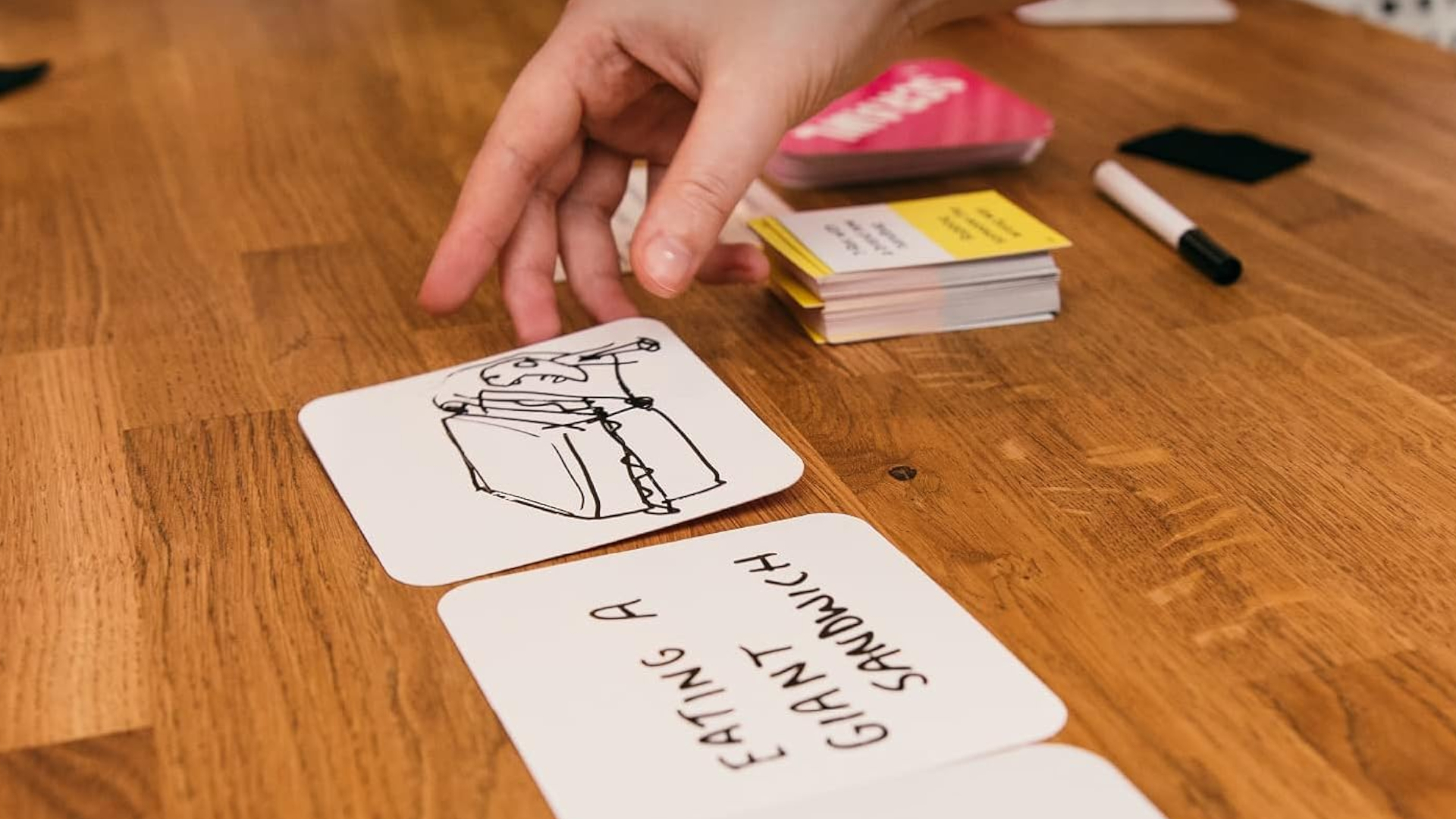 A hand reaches out for a card on a wooden table