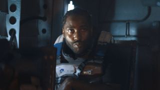 John David Washington sits waiting for action in a transport in The Creator.