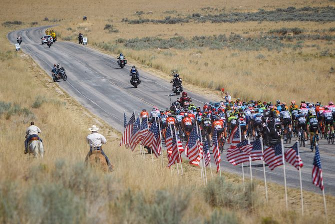 Riders on horseback ride next to the peloton at the start of stage 3 of the 2018 Tour of Utah