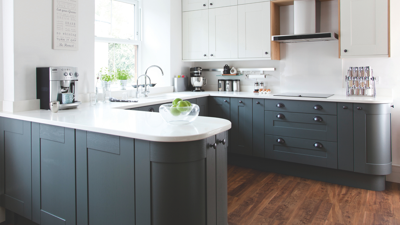  Fitted kitchen, white walls, grey units, dark wood flooring and ceiling beams.