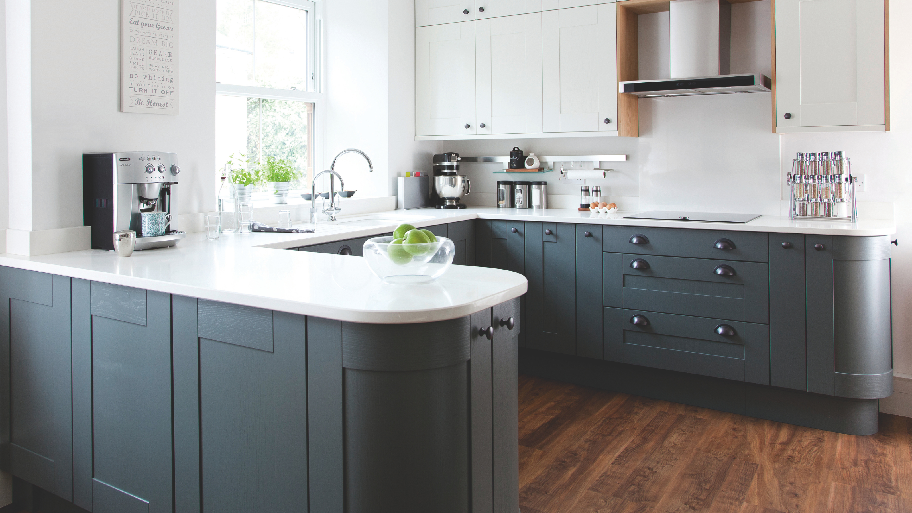 Fitted kitchen, white walls, grey units, dark wood flooring and ceiling beams.