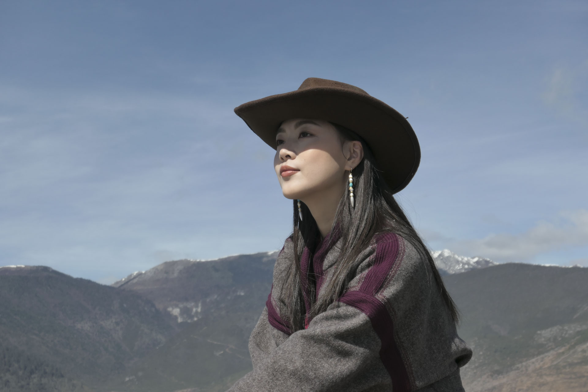 A woman in cowboy hat in front of a snowy mountain
