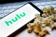 Hulu logo on a phone next to popcorn kernels