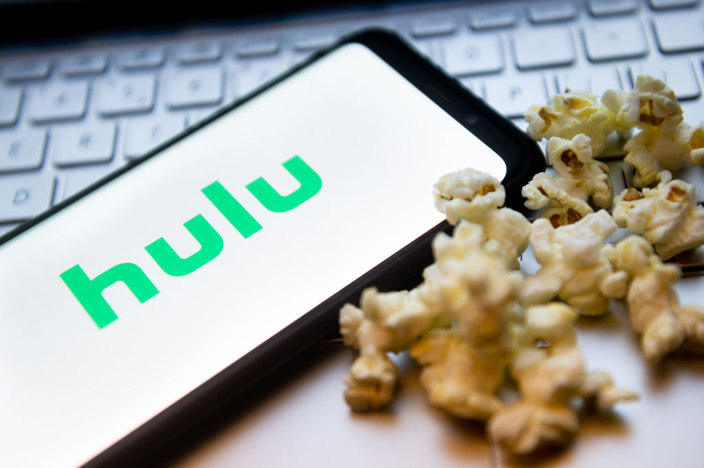 Hulu logo on a phone next to popcorn kernels