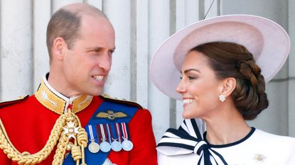 Prince William and Catherine, Princess of Wales smile at each other on the balcony of Buckingham Palace after attending Trooping the Colour on June 15, 2024 