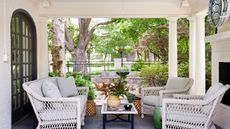 covered porch with white furniture and garden with mature trees