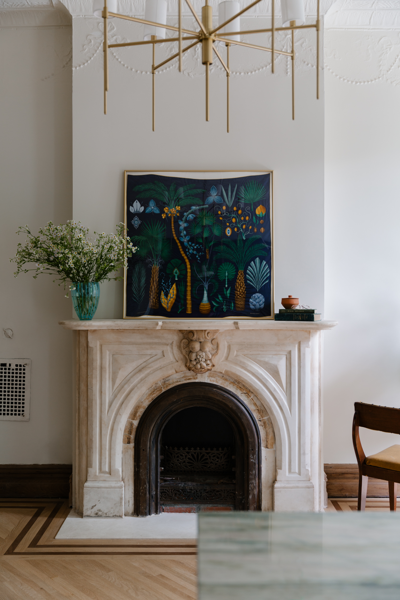 Antique brownstone living room interior featuring a marble fireplace mantle cover and vintage-inspired chandelier hanging above.