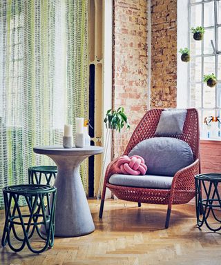 Bohemian living room ideas illustrated with brick walls, long green drapes and wicker furniture.