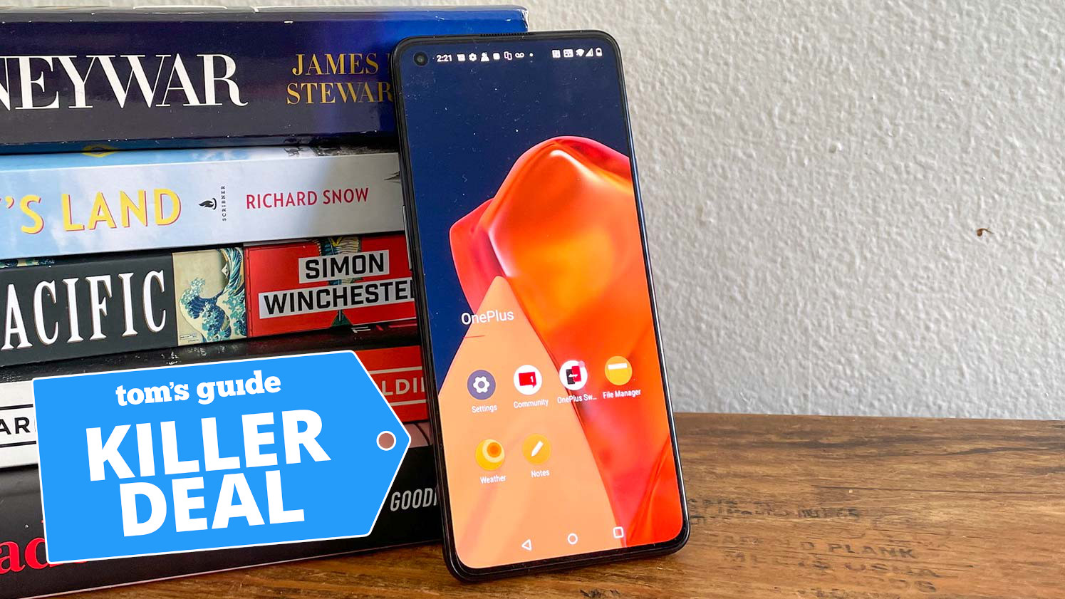 oneplus 9 in black leaning against books with killer deal tag