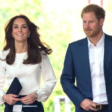 Kate Middleton, wearing a long-sleeved white top, smiles while walking with Prince Harry to launch the Heads Together Campaign on May 16, 2016