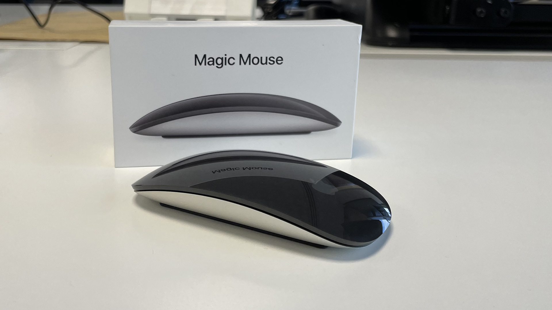 The Apple Magic Mouse sat next to its box.
