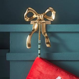 Gold Bow Metal Stocking Holder on a blue mantel.